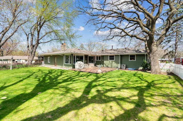 back of property with a lawn, a chimney, and a fenced backyard