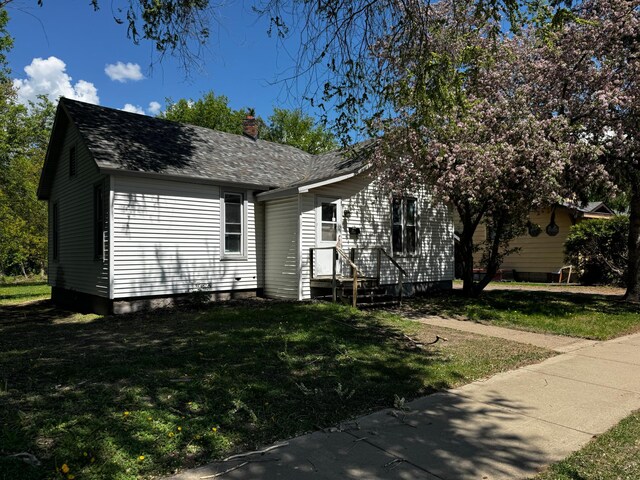 128 4th St NW, Aitkin, MN 56431 - view of front of home with a chimney, a front lawn, and a shingled roof