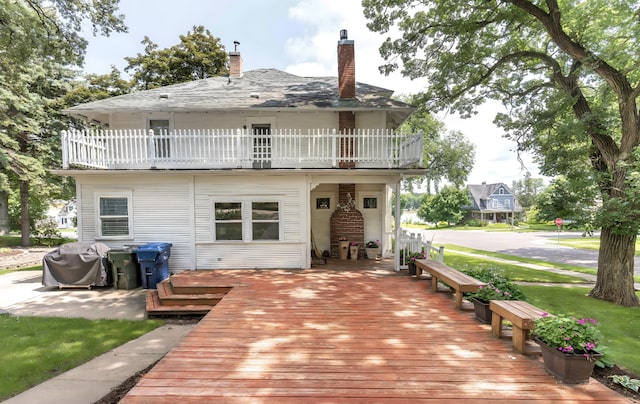 back of house with a chimney and a balcony