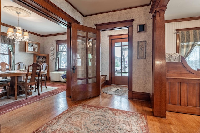 foyer entrance with a notable chandelier, a wealth of natural light, hardwood / wood-style flooring, and wallpapered walls
