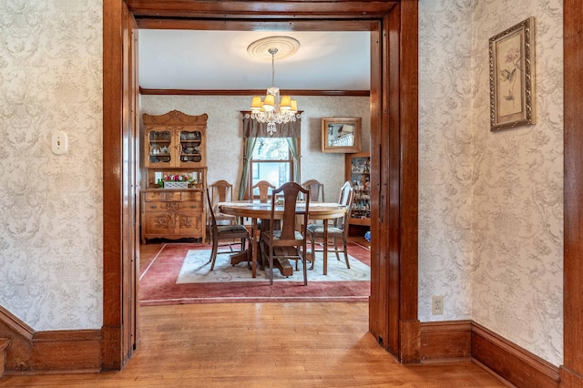 dining area with wood finished floors, a chandelier, and wallpapered walls