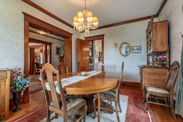 dining area featuring an inviting chandelier, crown molding, wood finished floors, and wallpapered walls