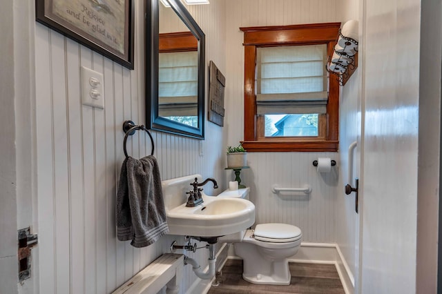 half bathroom with baseboards, a sink, wood finished floors, and toilet