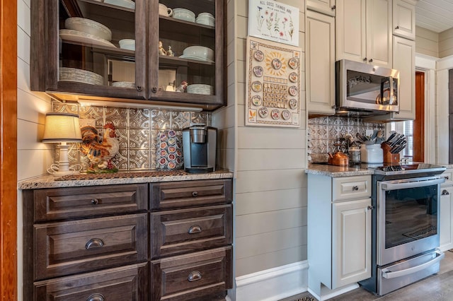bar featuring wood finished floors, appliances with stainless steel finishes, a bar, and tasteful backsplash