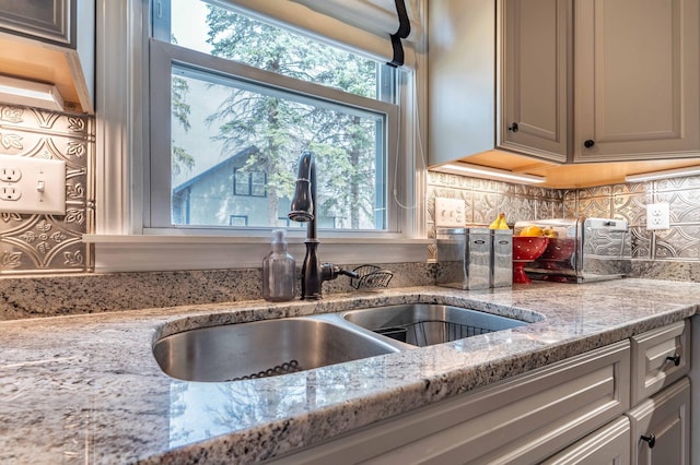 kitchen with light stone counters, a sink, and tasteful backsplash