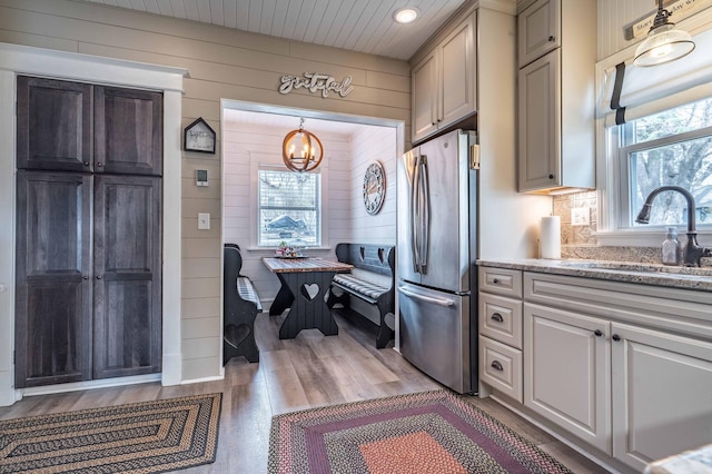 kitchen featuring a sink, plenty of natural light, freestanding refrigerator, and a notable chandelier