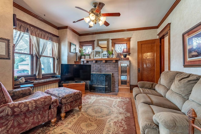 living area with crown molding, a ceiling fan, wood finished floors, and a brick fireplace