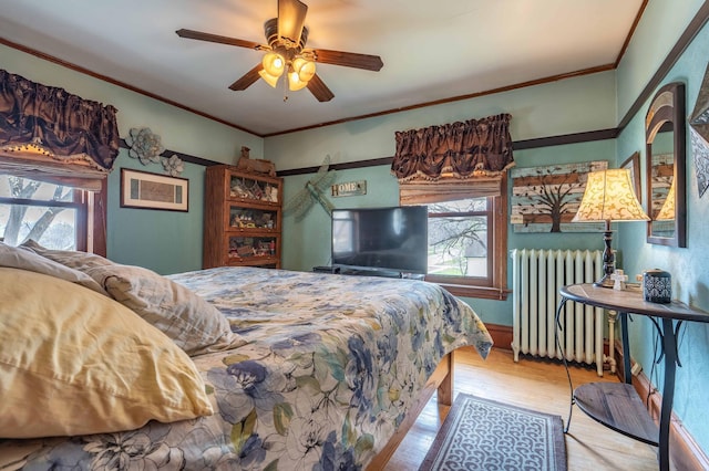bedroom featuring radiator heating unit, multiple windows, wood finished floors, and crown molding