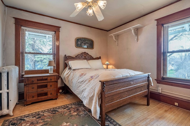 bedroom with ceiling fan, ornamental molding, and light wood finished floors