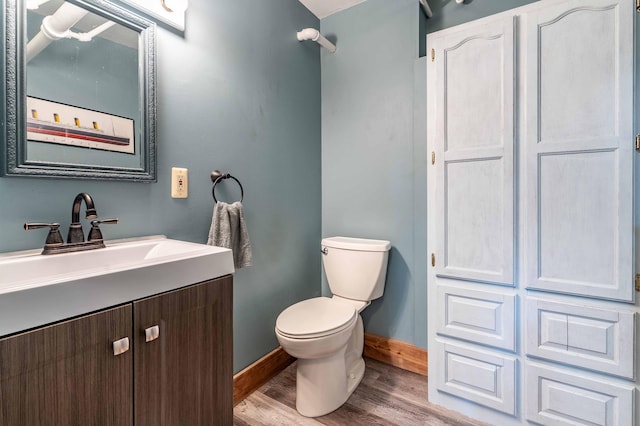 bathroom featuring vanity, baseboards, wood finished floors, and toilet