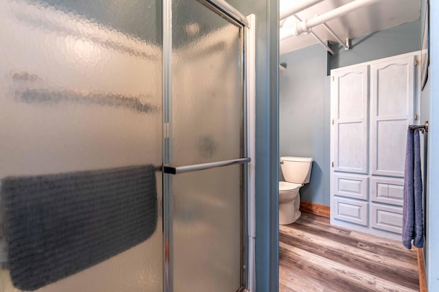 full bathroom with baseboards, wood finished floors, toilet, and a shower stall