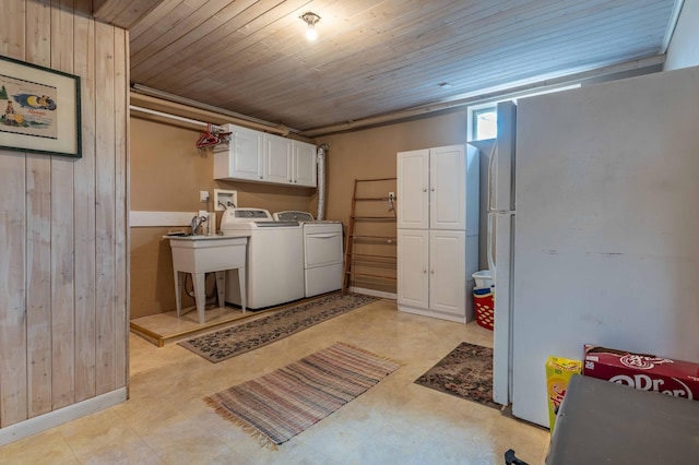 washroom featuring wood walls, washer and dryer, light floors, wood ceiling, and cabinet space
