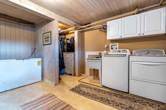 clothes washing area with wood ceiling, wood walls, cabinet space, and washer and dryer