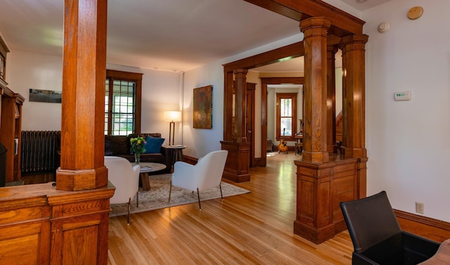 1043 Lincoln Ave, Saint Paul, MN 55105 - living room featuring ornate columns, radiator, light wood-type flooring, and healthy amount of natural light