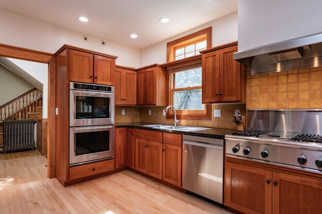 1043 Lincoln Ave, Saint Paul, MN 55105 - kitchen featuring appliances with stainless steel finishes, wall chimney exhaust hood, a sink, light wood finished floors, and brown cabinets