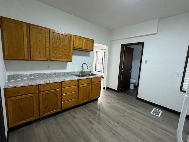 15 1st St SE, Melrose, MN 56352 - kitchen featuring brown cabinetry, a sink, dark wood-type flooring, and visible vents