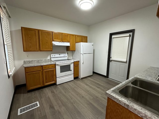 15 1st St SE, Melrose, MN 56352 - kitchen with brown cabinetry, visible vents, a sink, under cabinet range hood, and white appliances
