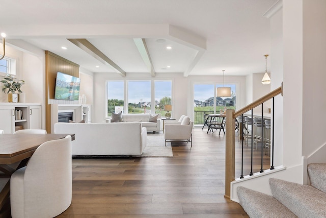 living room with stairs, a glass covered fireplace, beam ceiling, recessed lighting, and dark wood finished floors