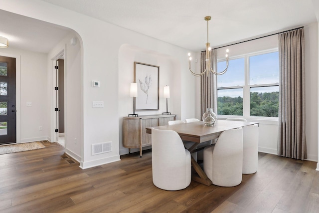 dining room featuring baseboards, a notable chandelier, visible vents, and wood finished floors