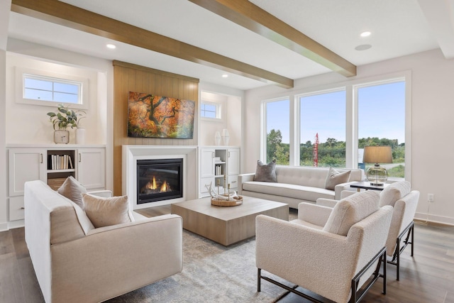 living room featuring recessed lighting, beamed ceiling, a glass covered fireplace, and wood finished floors