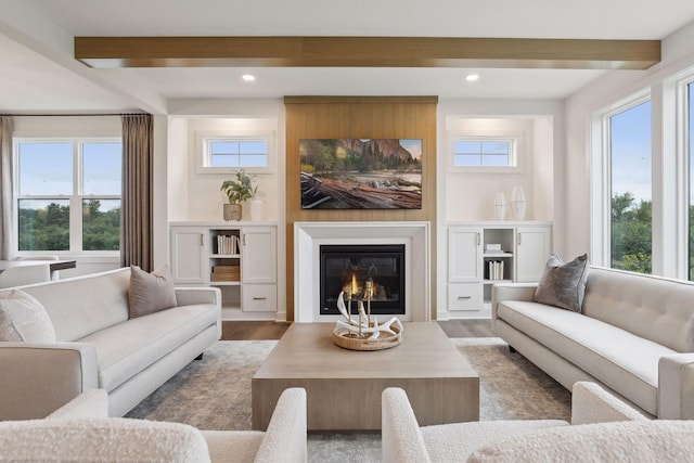 living room featuring a healthy amount of sunlight, recessed lighting, beam ceiling, and wood finished floors