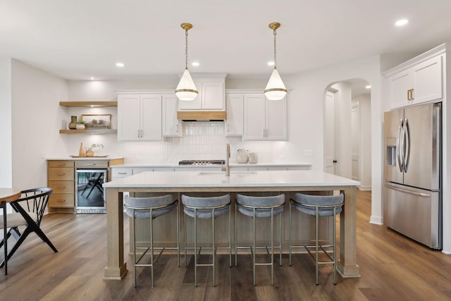 kitchen with appliances with stainless steel finishes, open shelves, a sink, light countertops, and wine cooler