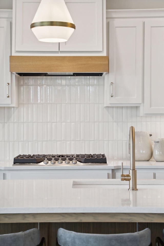 kitchen with backsplash, white cabinets, and light countertops