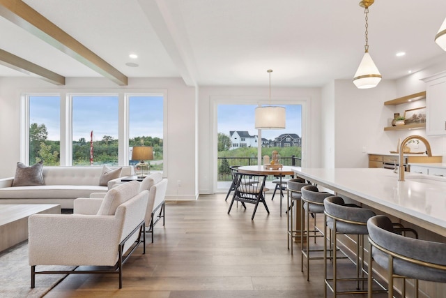 living room featuring baseboards, recessed lighting, beamed ceiling, and wood finished floors