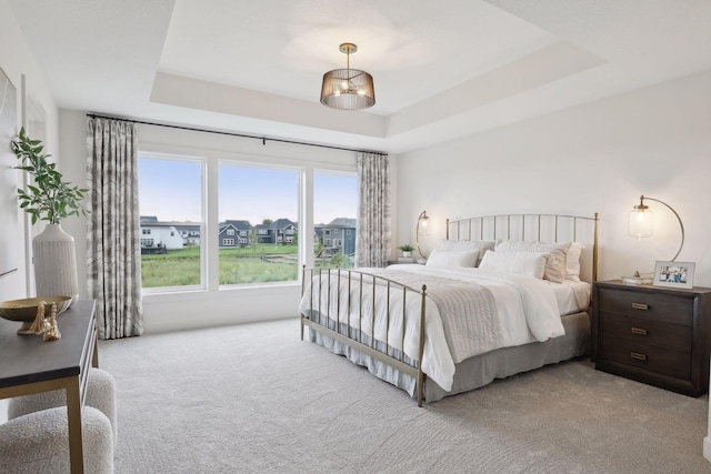 bedroom with a tray ceiling and light carpet