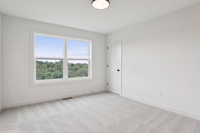 empty room featuring baseboards, visible vents, and light colored carpet