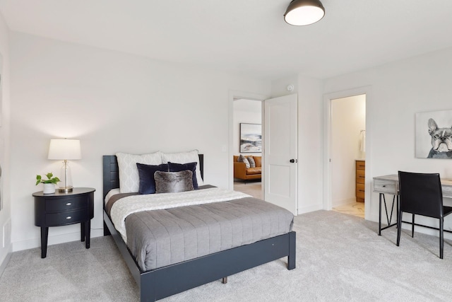 bedroom featuring connected bathroom and light colored carpet