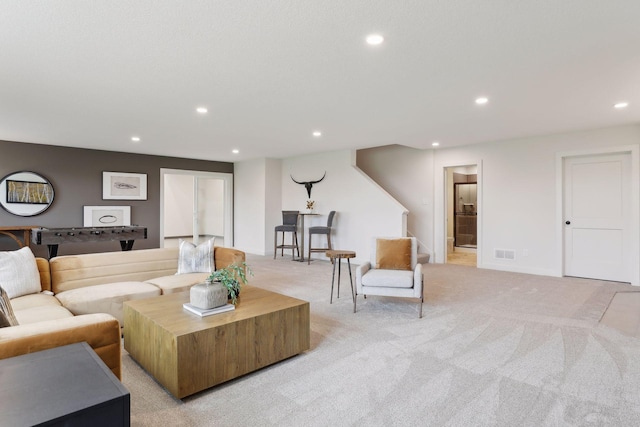 living area with recessed lighting, visible vents, and light carpet