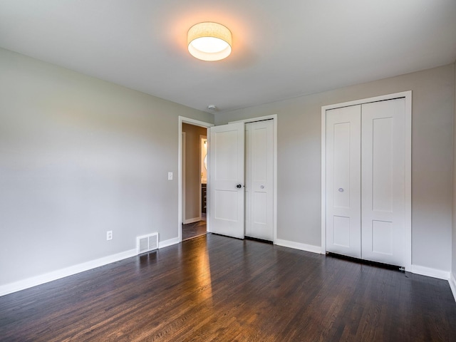 unfurnished bedroom featuring visible vents, baseboards, and dark wood finished floors