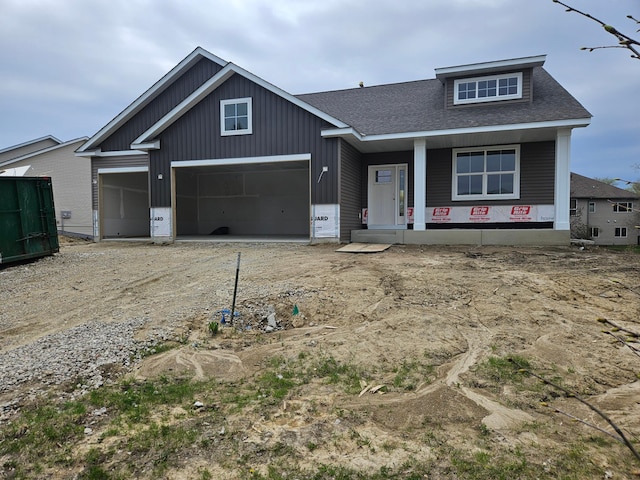 view of front of house featuring a garage, covered porch, a shingled roof, board and batten siding, and driveway
