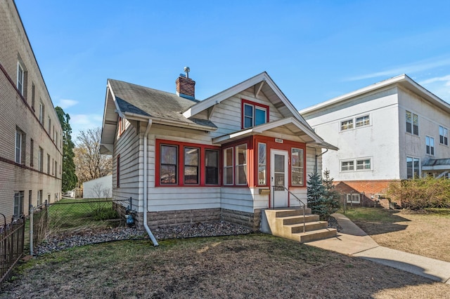 view of front of home featuring fence, a chimney, and a shingled roof