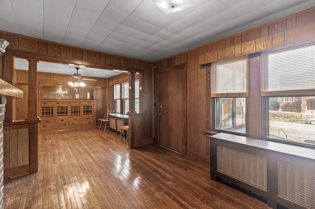 interior space with plenty of natural light, radiator, and wooden walls