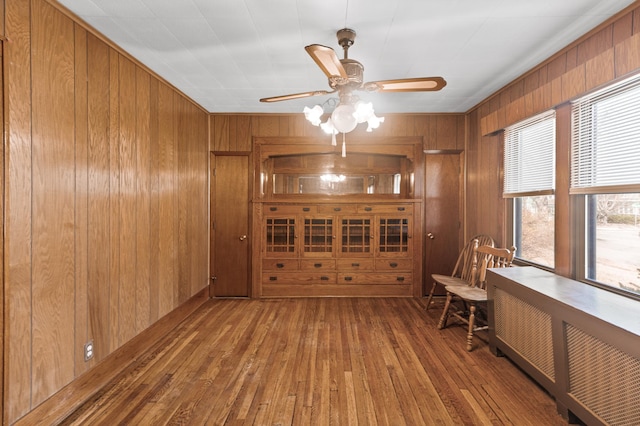 interior space featuring wooden walls, a ceiling fan, hardwood / wood-style flooring, and radiator