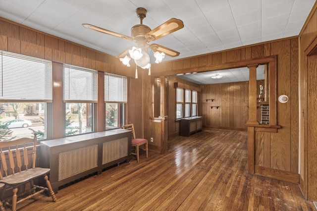 interior space with wood-type flooring, ceiling fan, and wood walls
