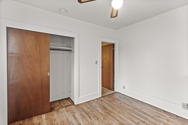 unfurnished bedroom featuring wood-type flooring, a ceiling fan, baseboards, and a closet