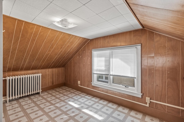 additional living space featuring radiator, wood walls, and lofted ceiling