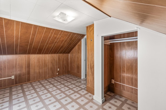 additional living space with wooden walls, light floors, and vaulted ceiling