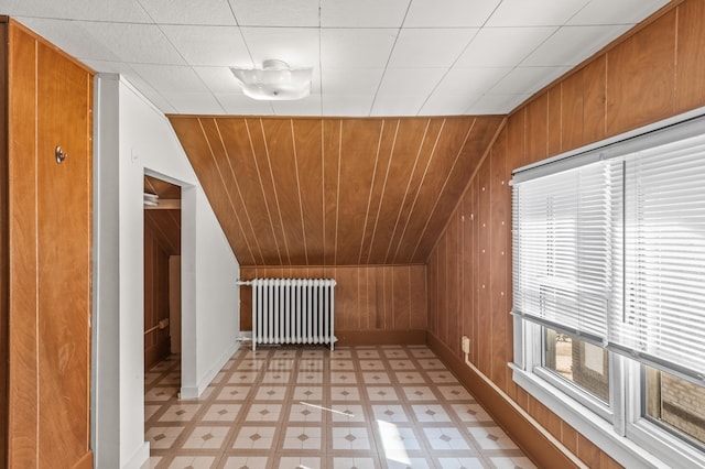 bonus room featuring baseboards, vaulted ceiling, radiator, and light floors