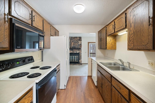 kitchen featuring black microwave, white dishwasher, a sink, electric stove, and light wood-style flooring