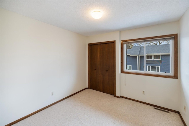 unfurnished bedroom featuring visible vents, baseboards, light carpet, and a closet