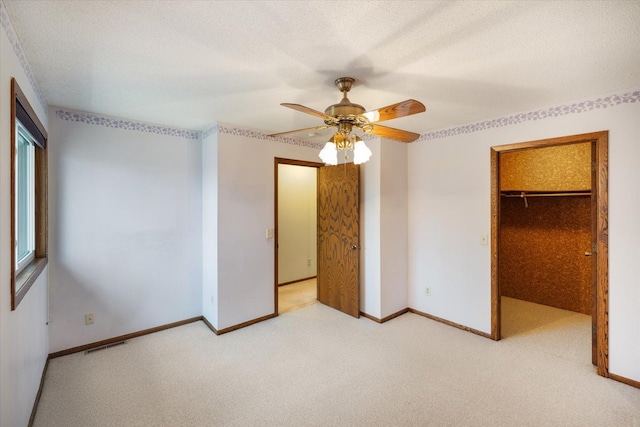 unfurnished bedroom with ceiling fan, carpet floors, a spacious closet, visible vents, and a closet