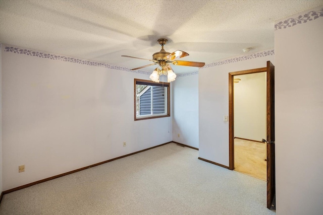 spare room with a ceiling fan, a textured ceiling, light carpet, and baseboards