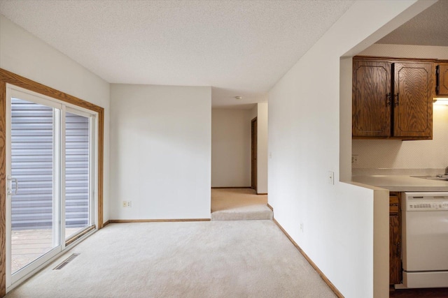 interior space featuring light carpet, dishwasher, light countertops, a textured ceiling, and visible vents