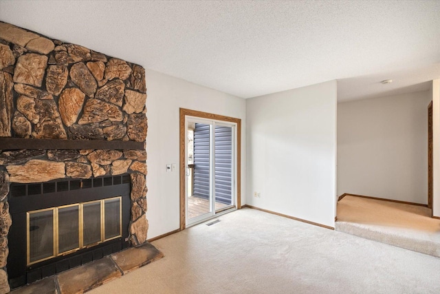 unfurnished living room featuring carpet floors, visible vents, a fireplace, baseboards, and a textured ceiling