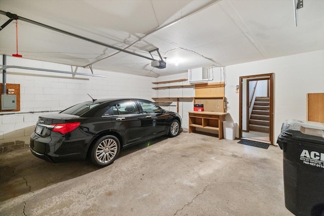 garage featuring a garage door opener, electric panel, and concrete block wall