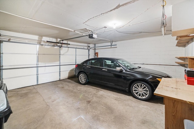 garage featuring concrete block wall and a garage door opener